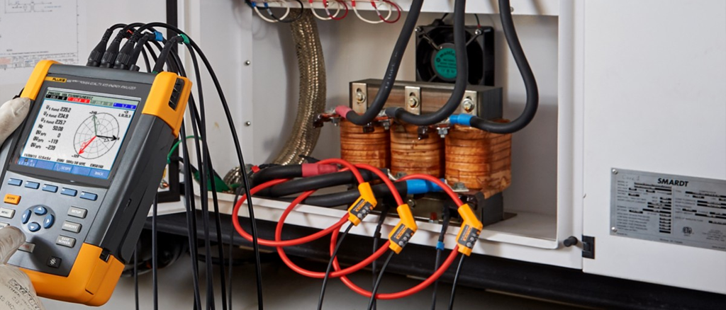 Electricista usando analizador de calidad de energía en un transformador.